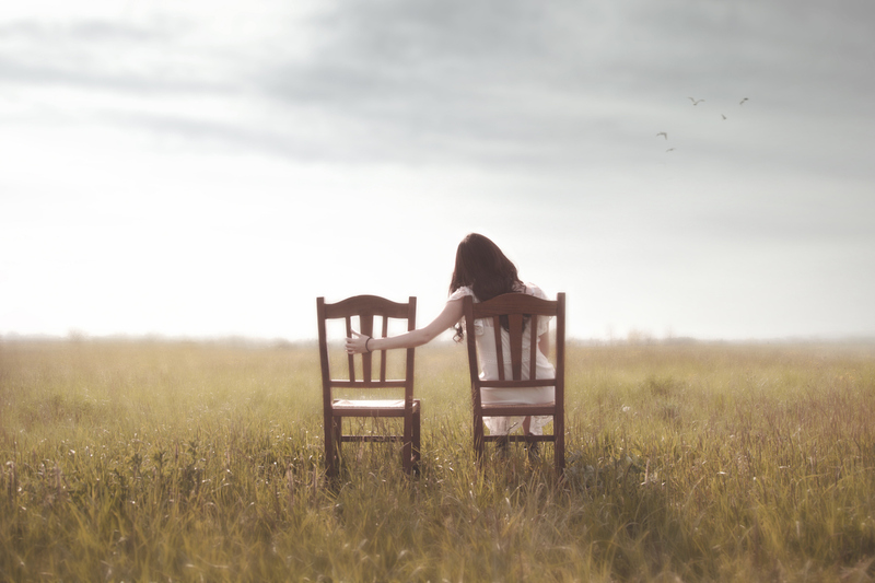 sad woman looks nostalgically at her lover's empty chair  in the middle of nature / fcscafeine sad woman looks nostalgically at her lover's empty chair  in the middle of nature